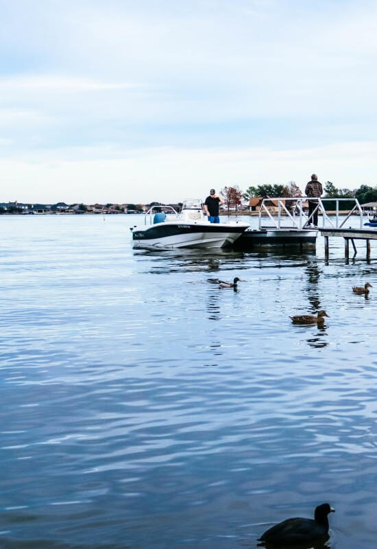 A man fishes on Lake Granbury surrounded by ducks in the water